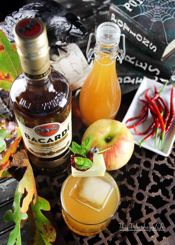 a bottle of Bacardi Gold on a grate with apples, apple cider and a cocktail