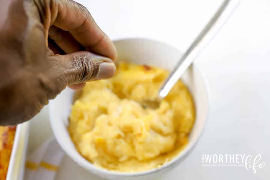 man's hand sprinkling salt onto a butternut squash in a white bowl