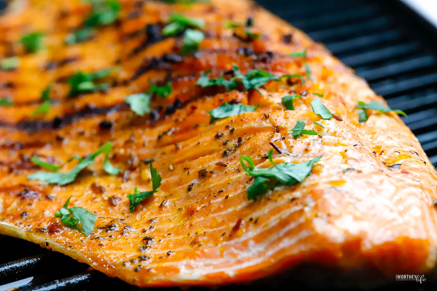 a large filet of cooked salmon with grill marks and topped with chopped cilantro