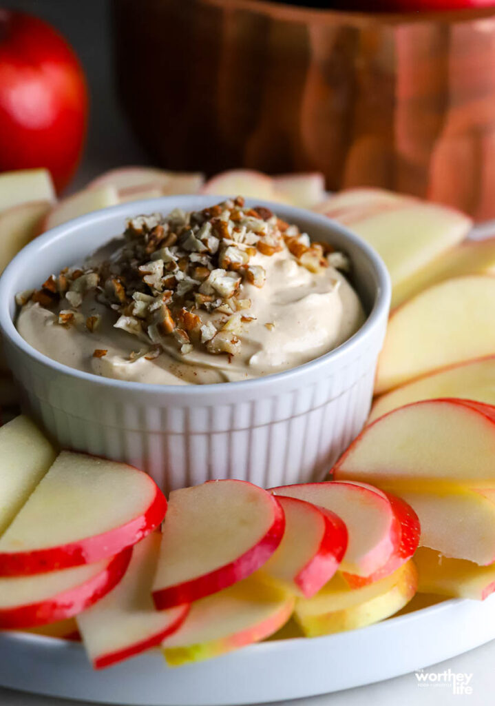 a caramel dip in a white ramekin with sliced apples