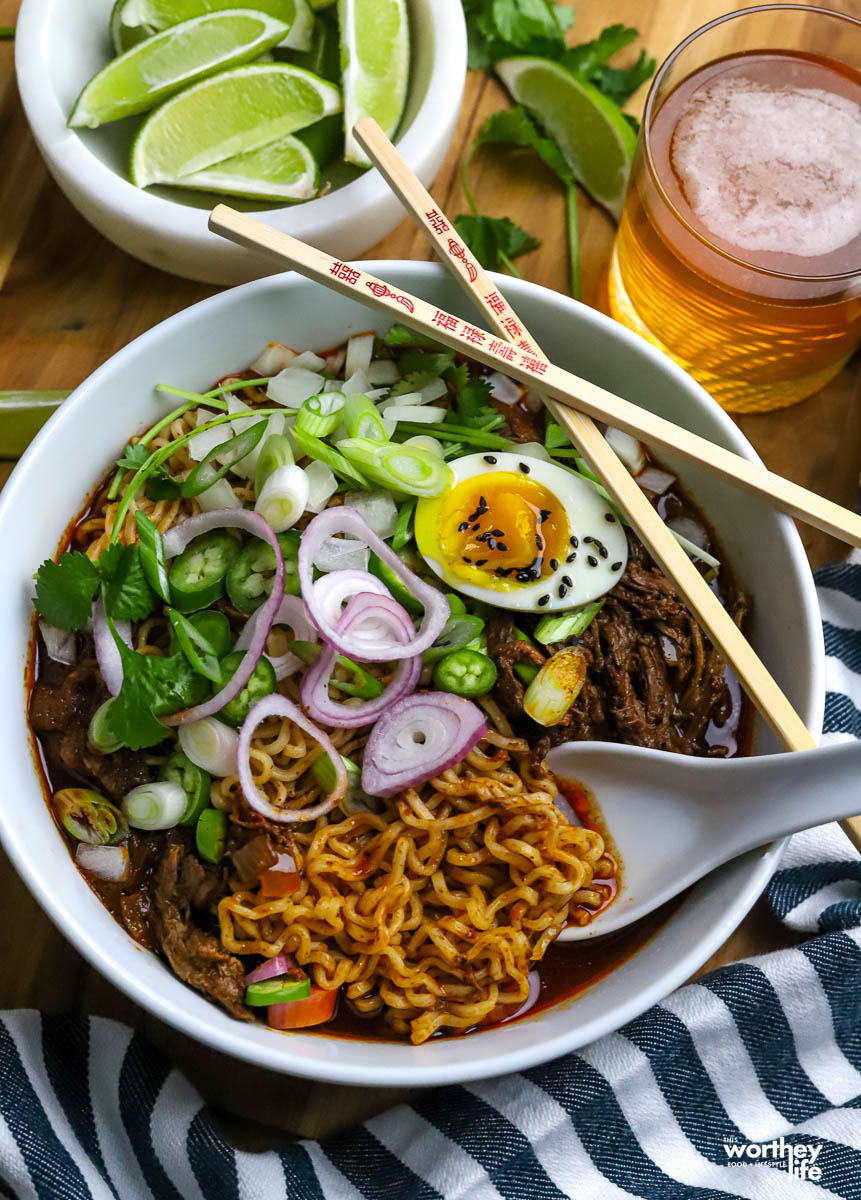 Mexican ramen noodles in a bowl with chopsticks and a spoon.