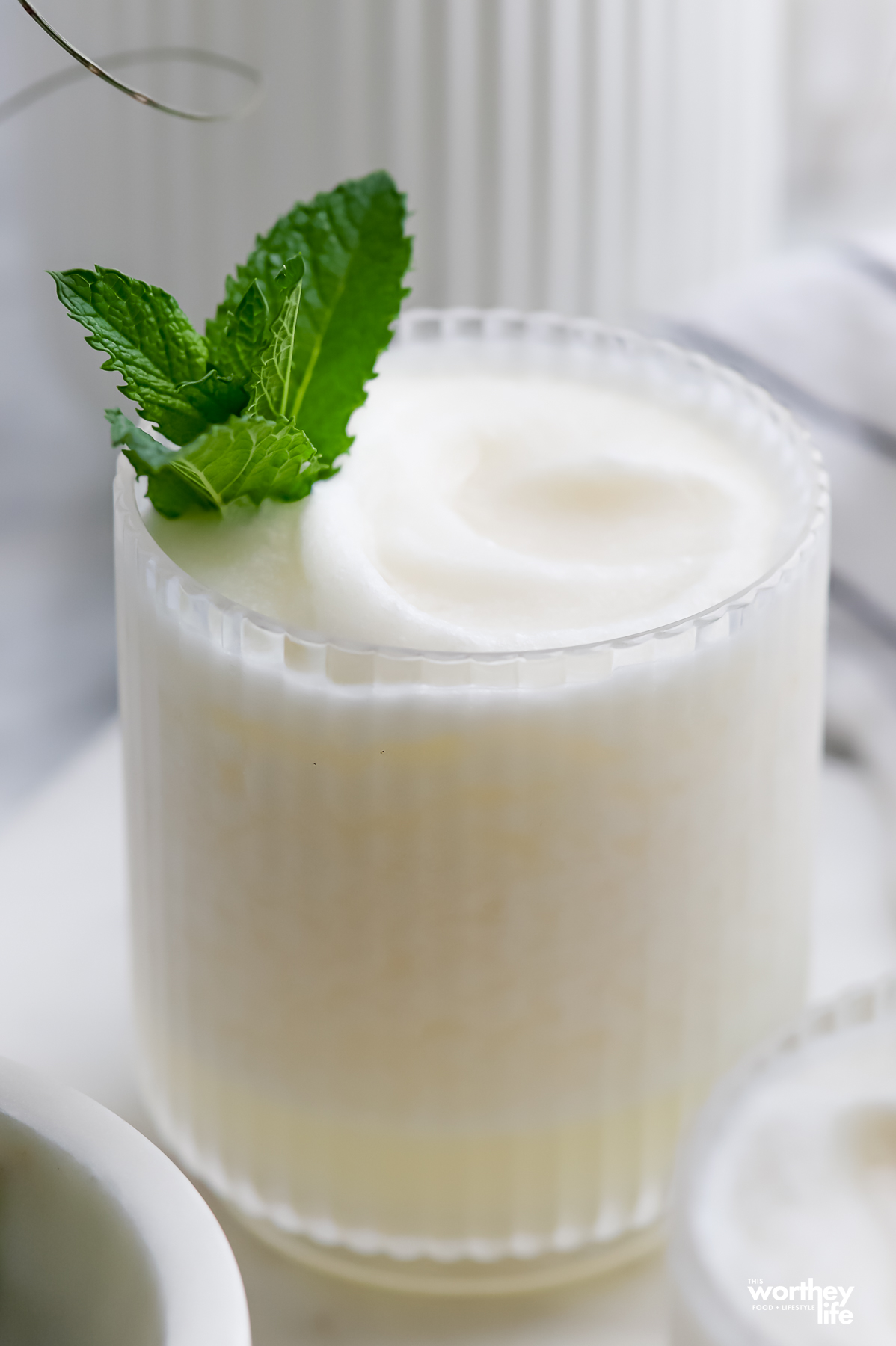 A glass filled with our frozen coconut margarita with fresh mint.