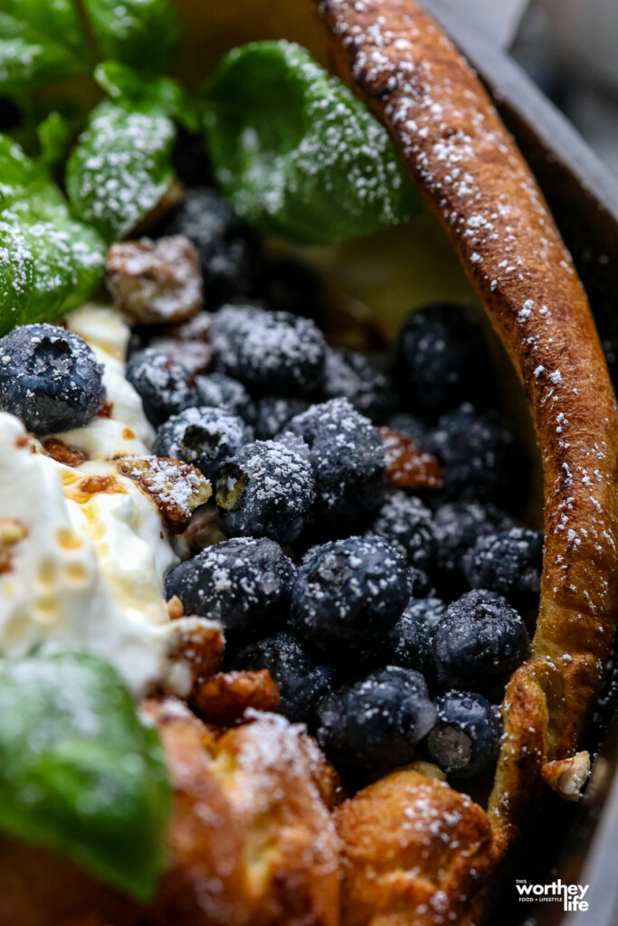 Partial view of our blueberry Dutch Baby in a cast iron skillet.