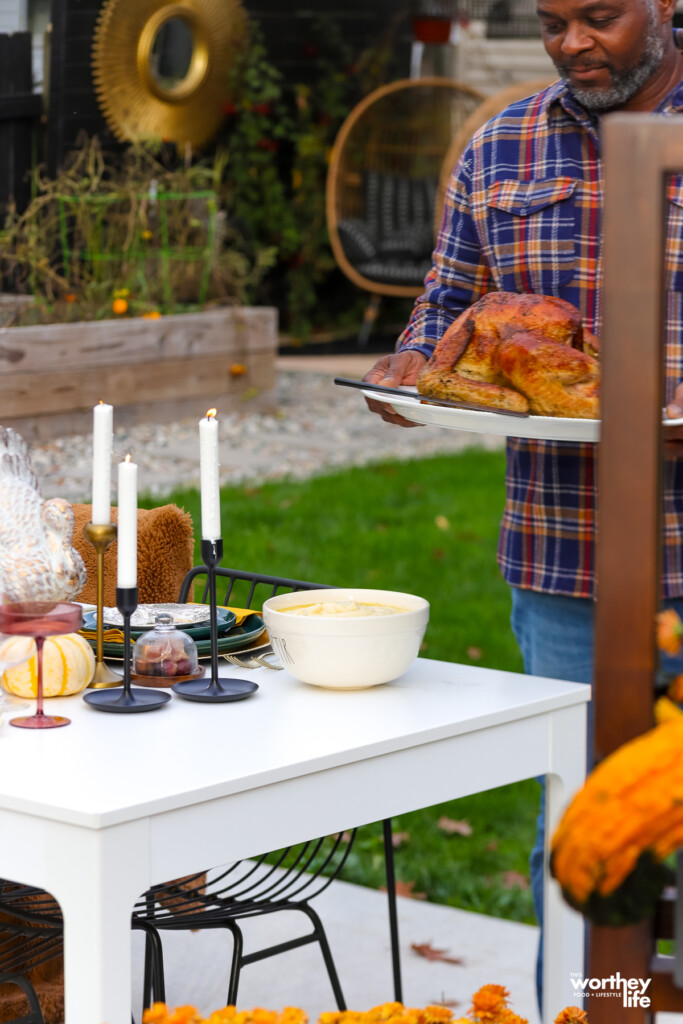 man setting a turkey on the table for dinner