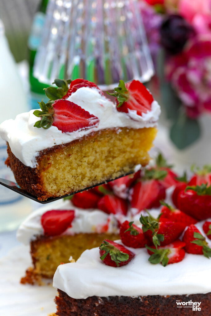 a slice of olive oil cake topped with whipped cream and strawberries
