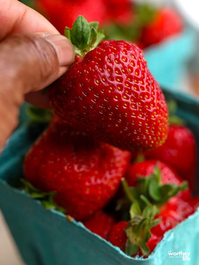 a man holding a fresh strawberry