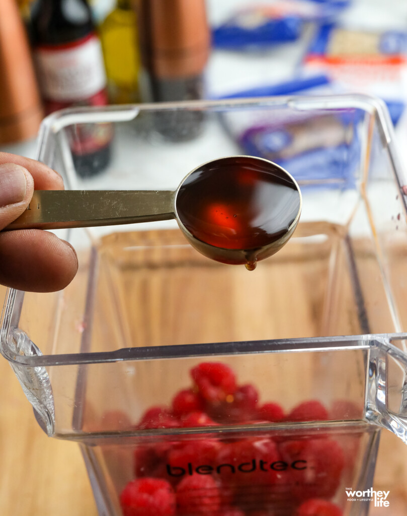 pouring honey into a blender to make a Raspberry Balsamic Vinaigrette
