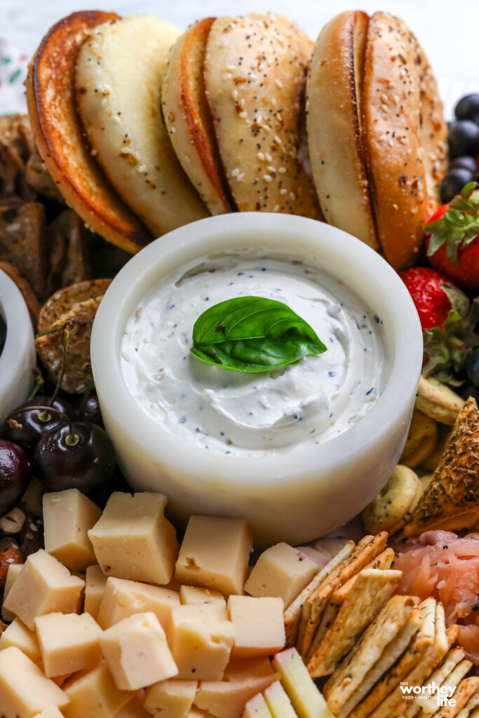 everything bagel yogurt dip on a platter with bagels, cheese