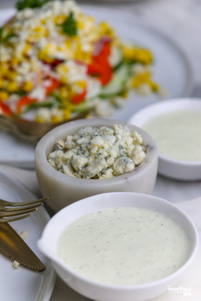 Gorgonzola cheese crumbles and yogurt dressing with a corn salad in the background