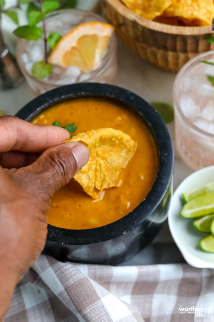 man dipping a crispy tortilla into homemade salsa in a black marble bowl
