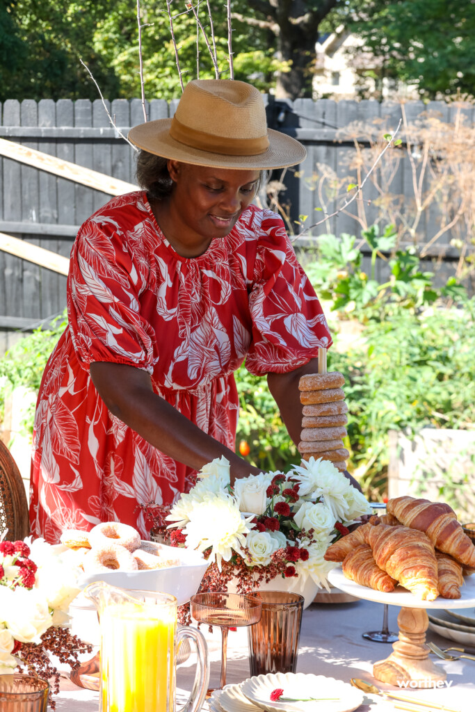 a woman putting donuts down on a table for brunch