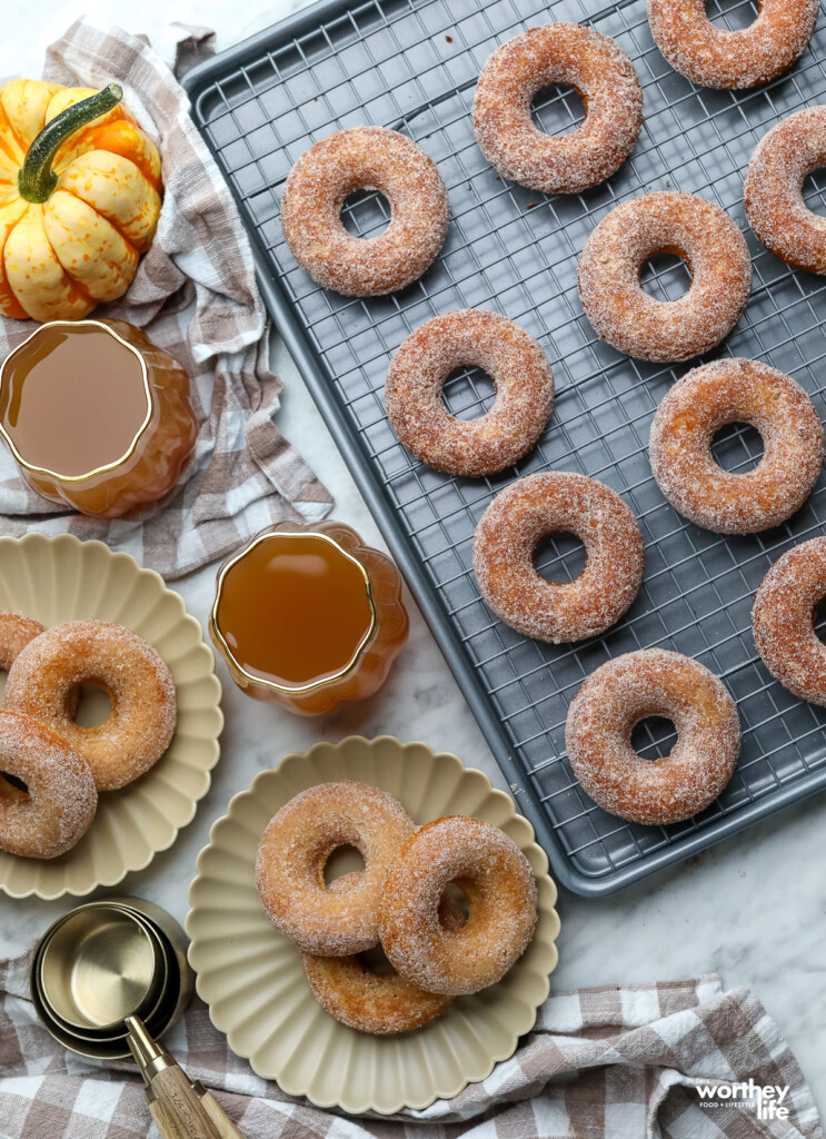 spiced apple donuts on a baking tray with apple cider