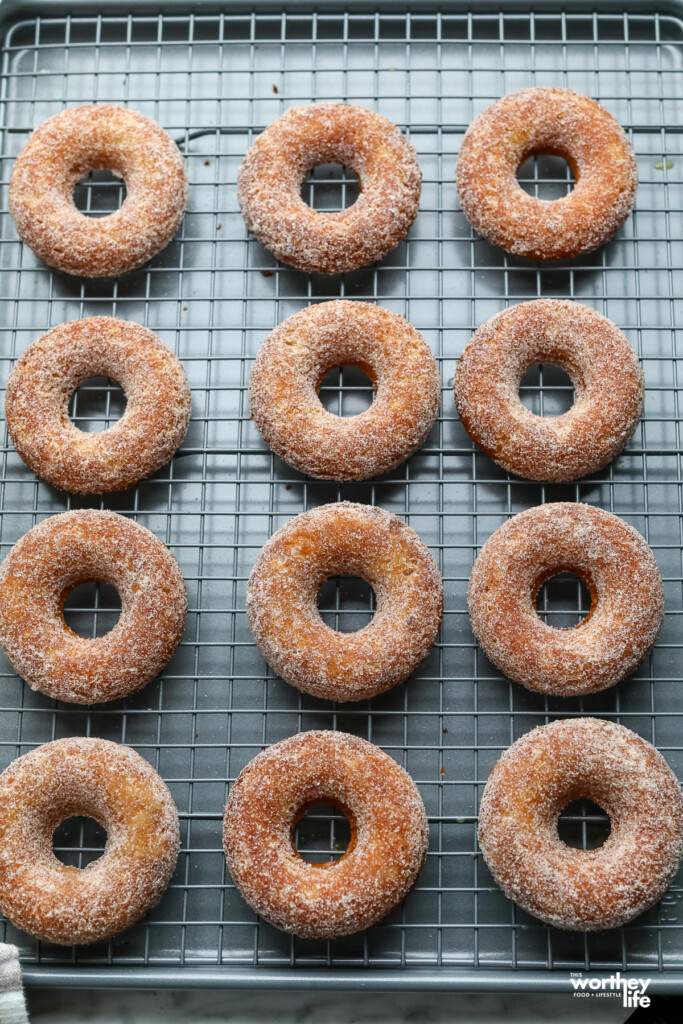 a baking sheet filled with baked apple cider donuts