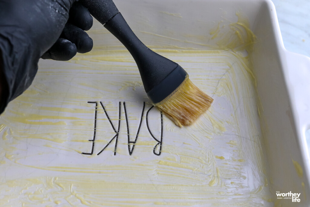 a man's hand using a baking brush inside a baking pan