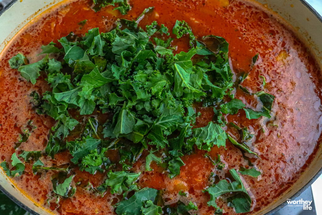 adding fresh kale into a soup