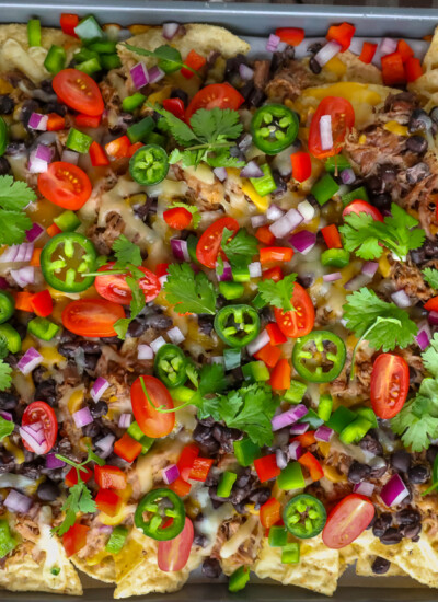 These easy Carnitas Nachos are loaded with Del Real Foods Carnitas, black beans, peppers, tomatoes, jalapeños, and melty Mexican cheese for the ultimate sheet-pan appetizer.