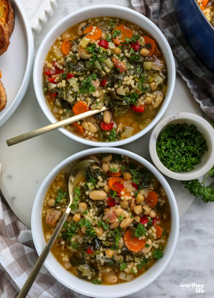 two bowls of Couscous Chickpea Cannellini Bean Soup in white bowls on a mable background