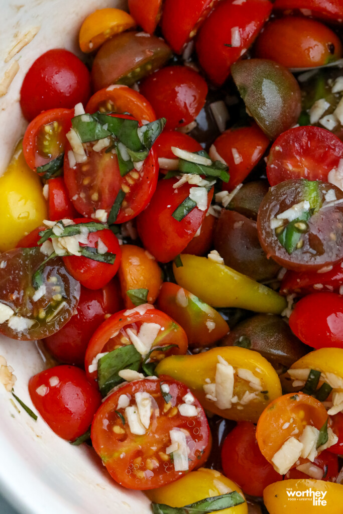 a bowl of cherry tomatoes mixed with cheese and balsamic vinegar