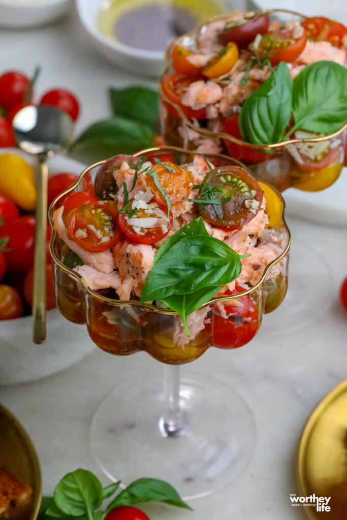 a tomato based bruschetta with salmon in a wavy clear glass
