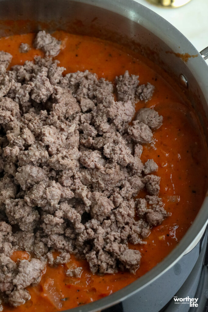 brown ground lamb in a pot with tomato paste