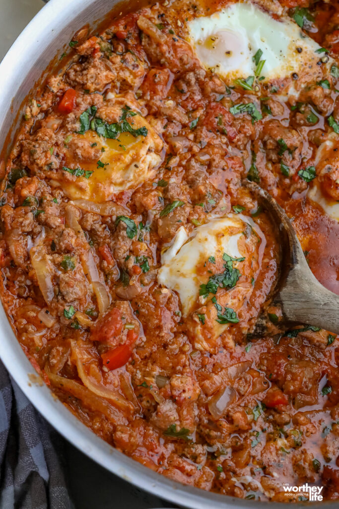 brunch or breakfast recipe with eggs, onions, tomato based dish in a pan