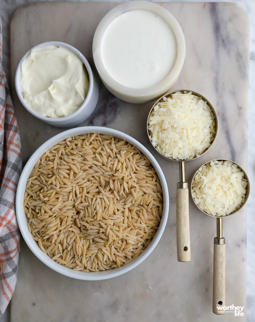 orzo, heavy cream, cheese ingredients on a white marble board