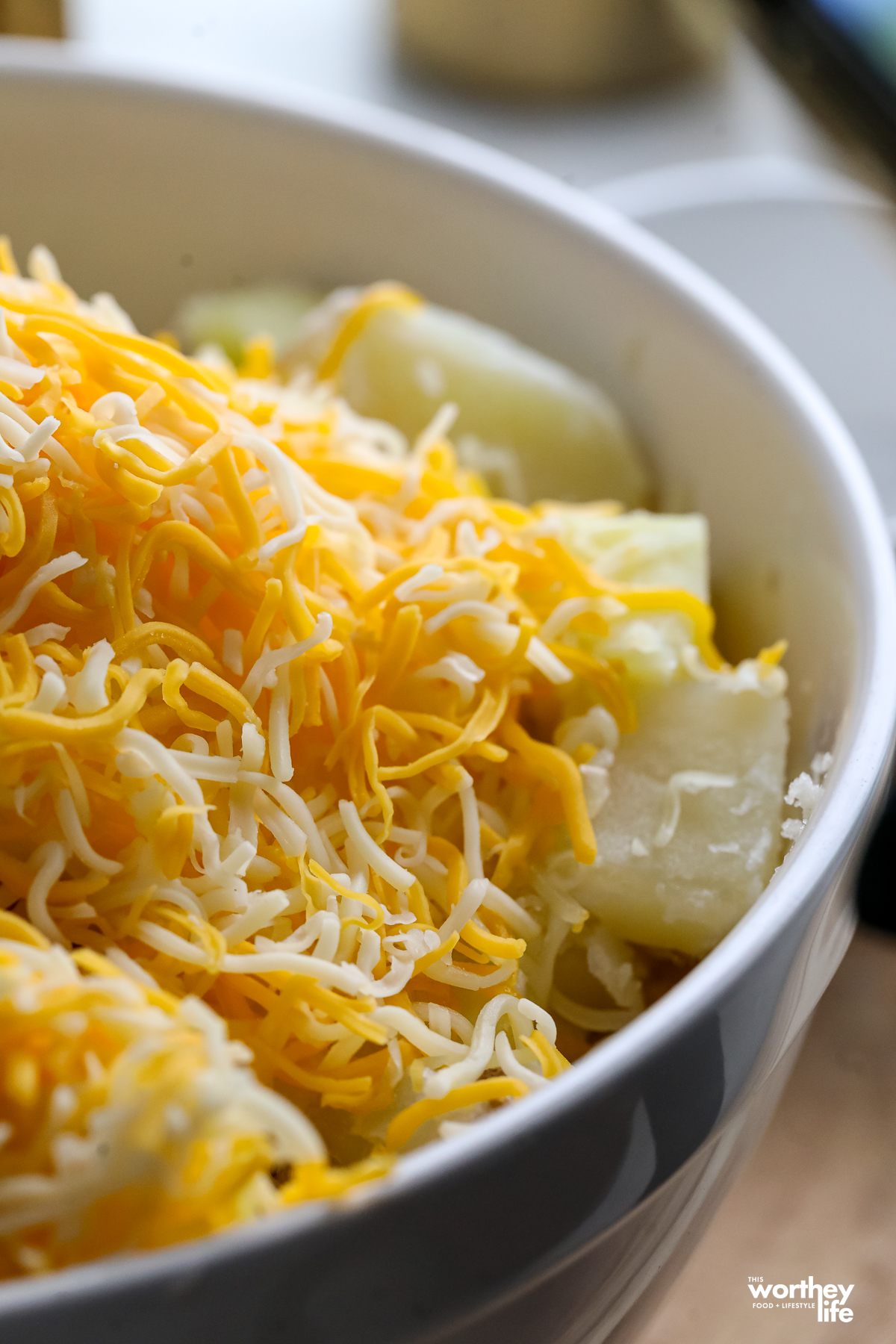 cheese topped over potatoes in a large bowl
