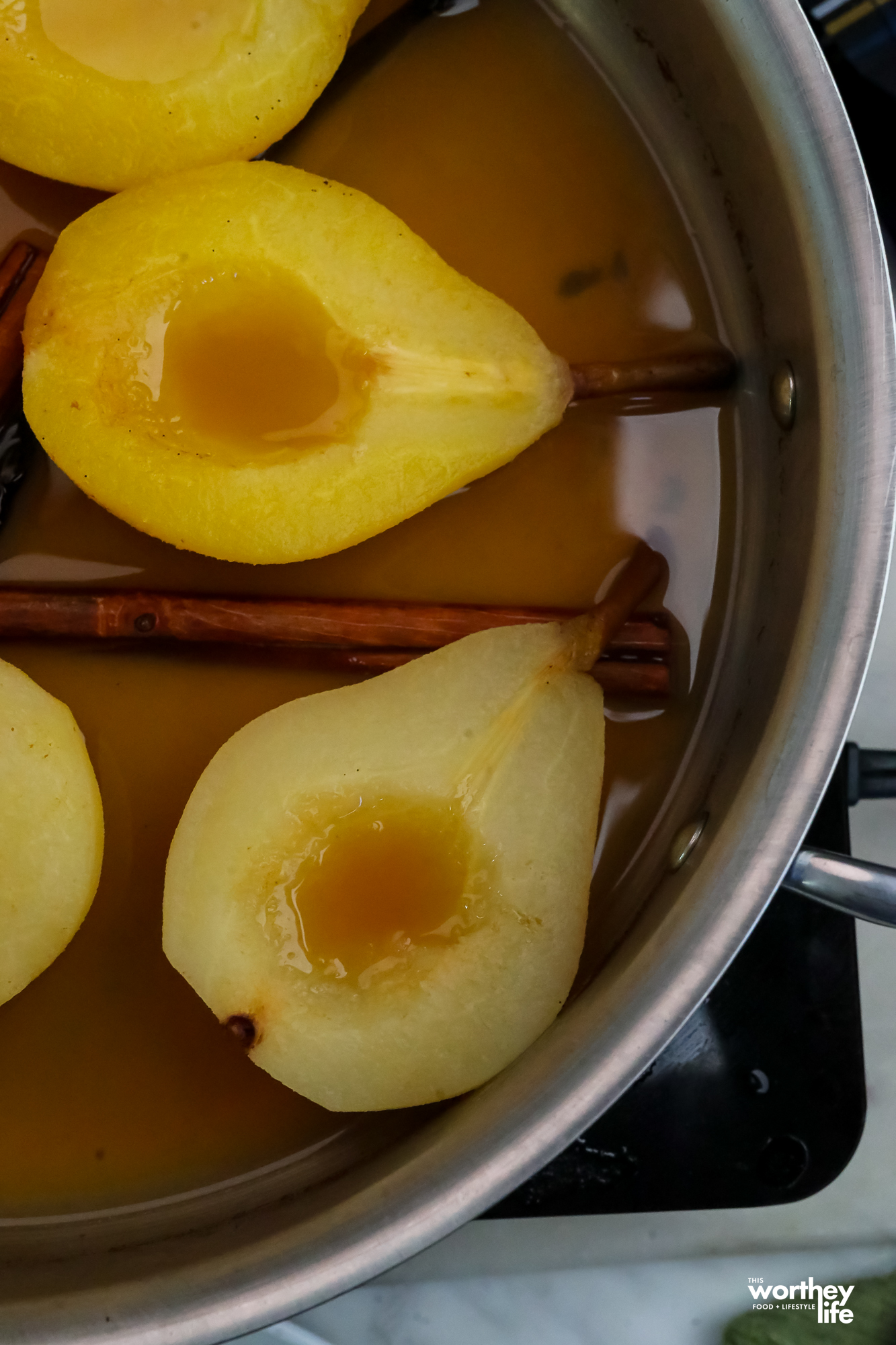 poached pears in apple cider sauce in a saucepan
